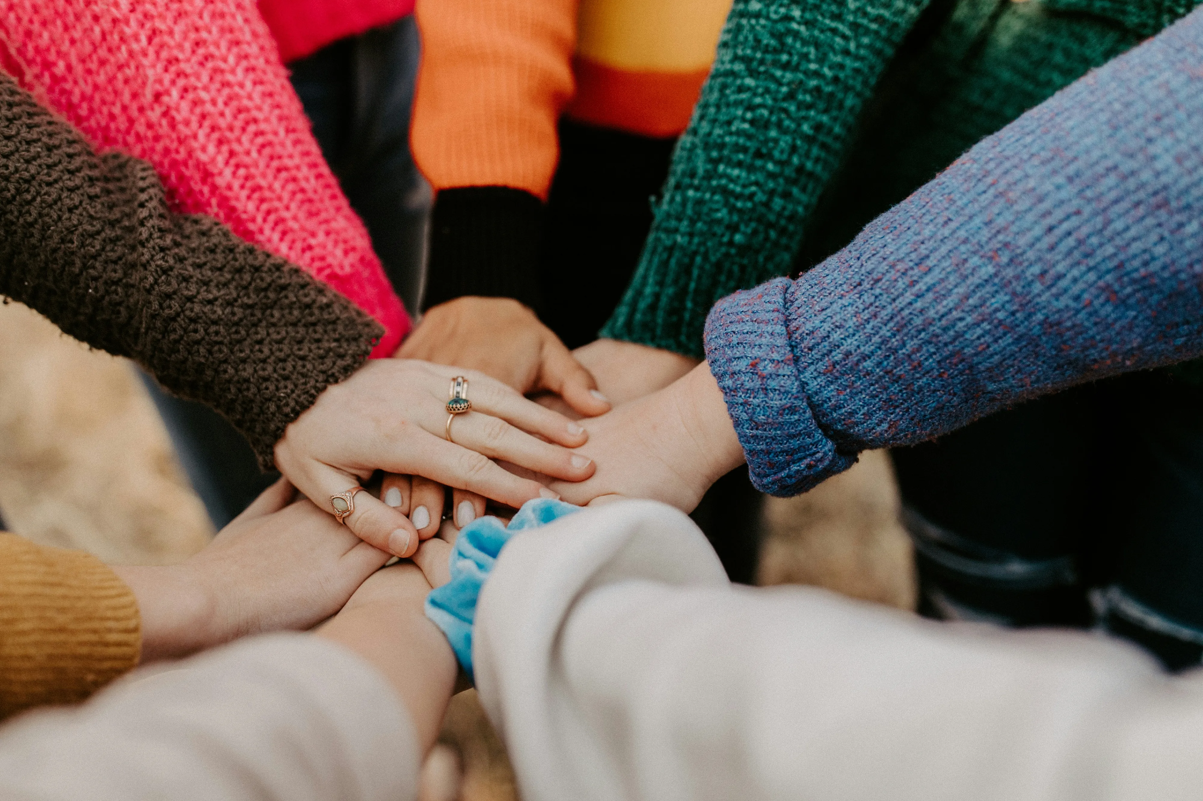 A circle of hands placing different symbolic tokens together on a map.