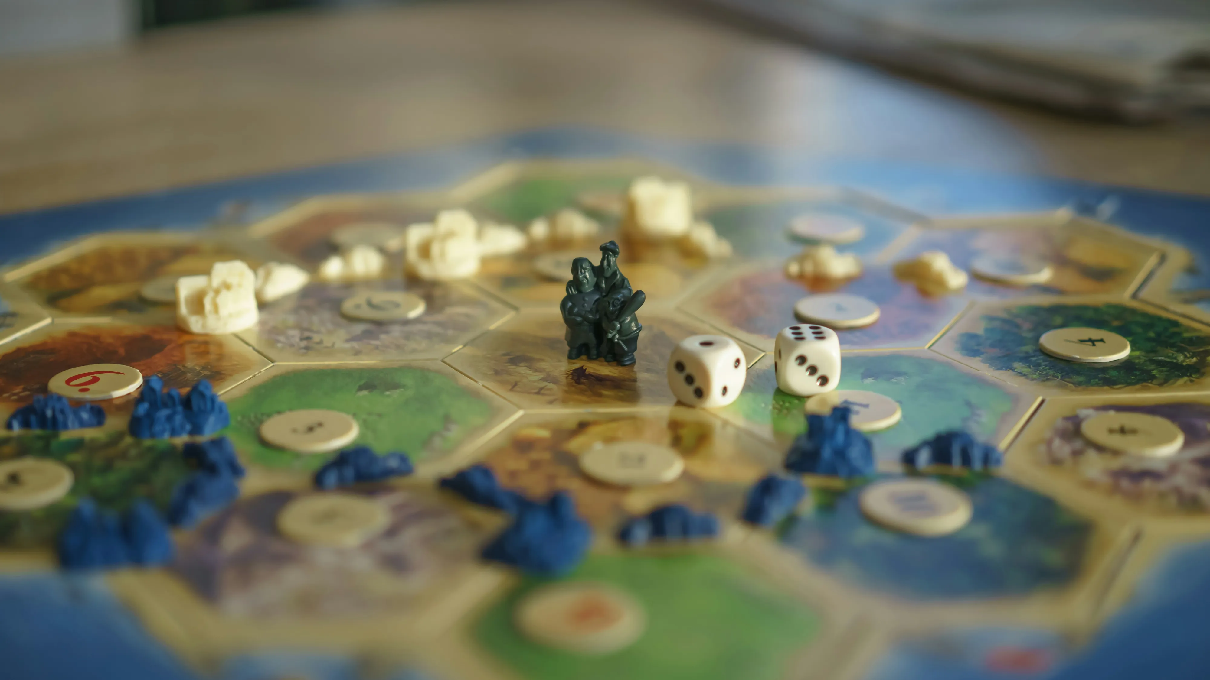 Friends around a warmly lit tabletop covered in dice, notebooks, illustrated cards, and a central fantasy map.